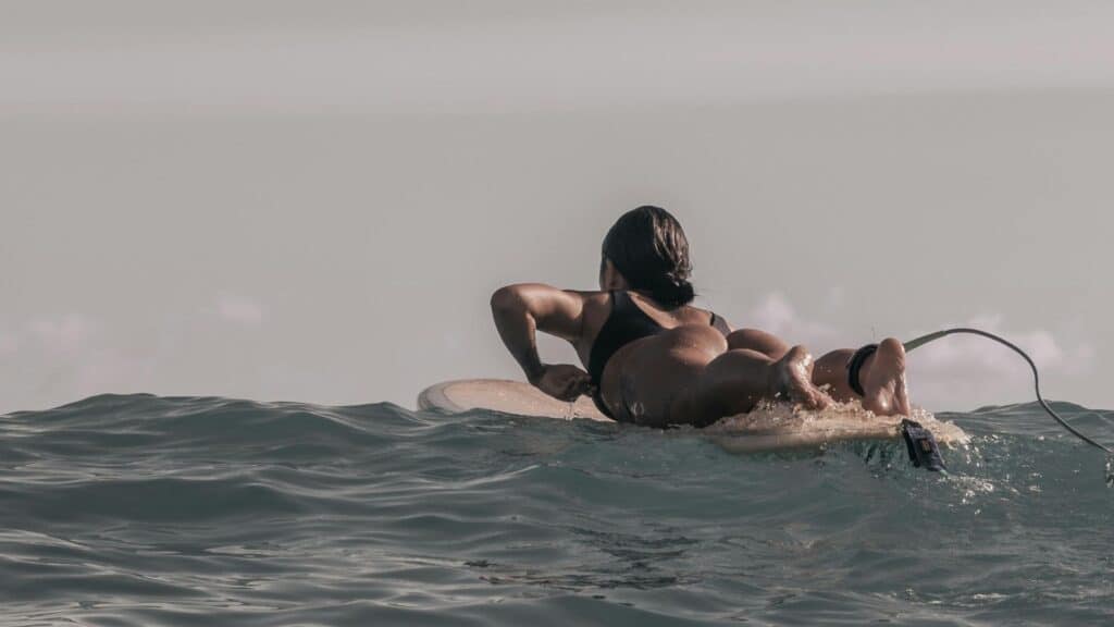 An image of a female surfer paddling out to sea she is getting a cardio workout