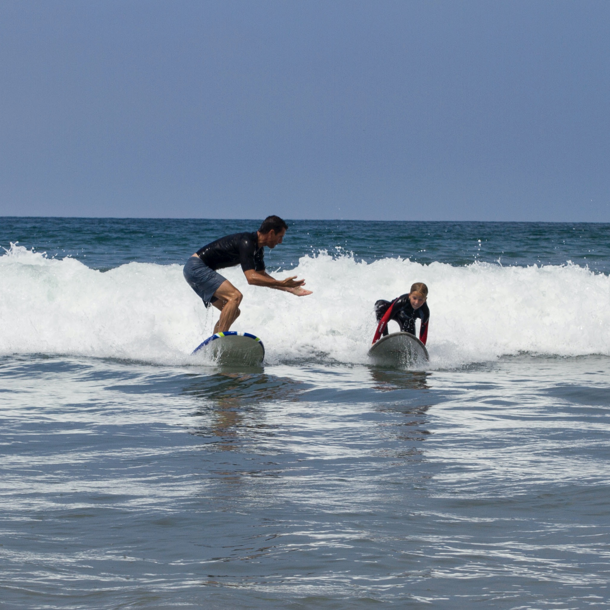 Father instructs daughter how to pop up and how to surf.