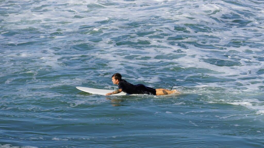 A surfer burning calories by paddling out to sea to catch a big wave