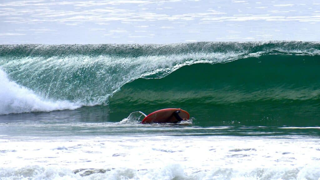 An image of a surfer burning calories from swimming with his surfboard after a wipeout