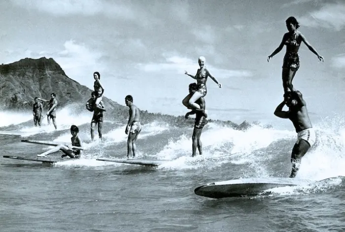 Couples tandem surfing in Hawaii in the early 1900s. 