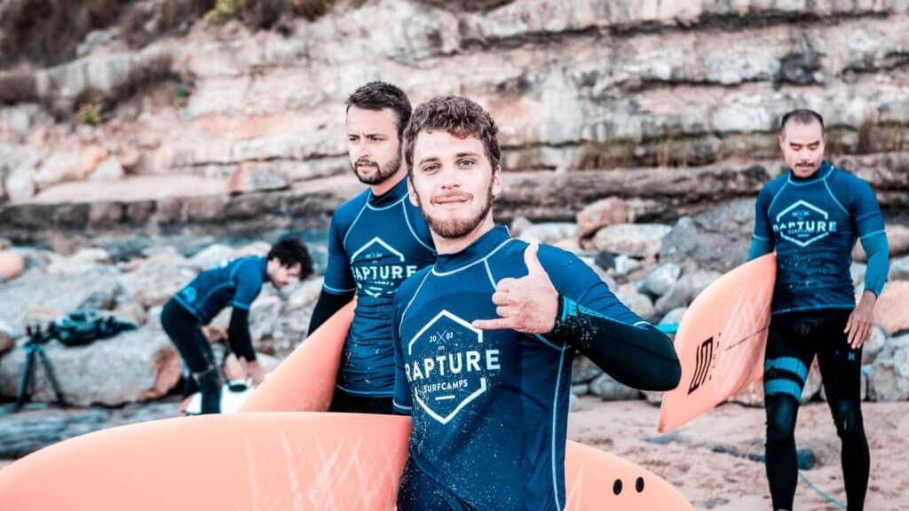 An image of surfers in Ericeira one is doing the shaka