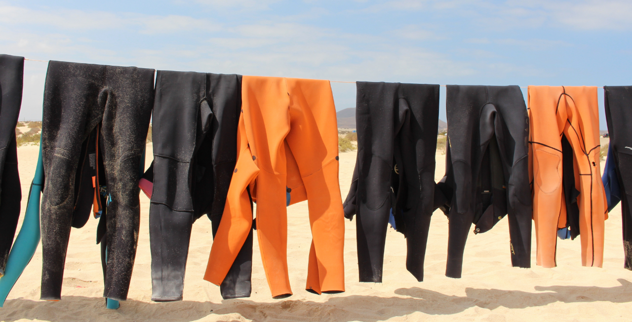 The ultimate guide to choosing the best wetsuits for surfing. Wetsuits hang drying on a line. 